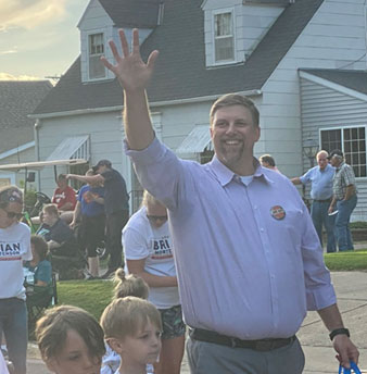 Brian Mortenson waving to on lookers on a parade route.